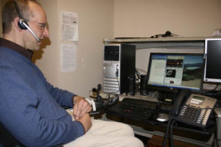 The author seated at computer using Dragon Naturally Speaking software.