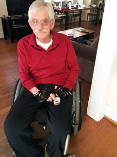 man in wheelchair pushes button on remote device to open front door